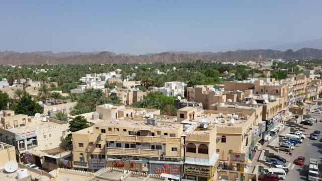 A Great Image view of Nizwa city from a high building, showing the mountains bordering the city also the palms in green color looks very amazing